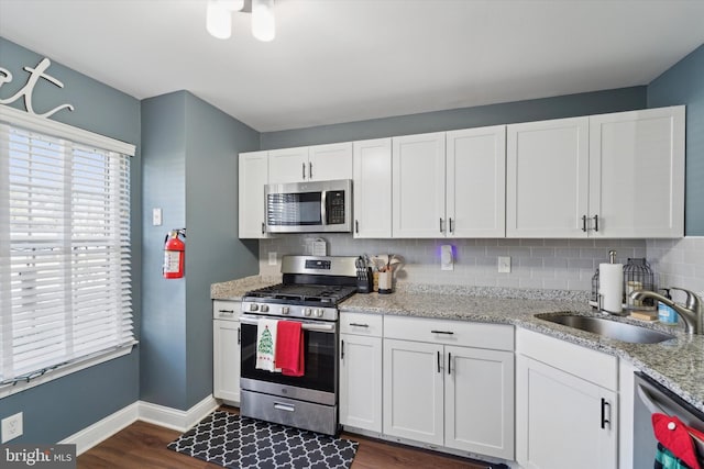 kitchen featuring white cabinetry, sink, stainless steel appliances, dark hardwood / wood-style flooring, and backsplash