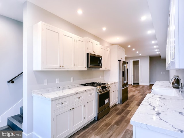 kitchen featuring dark wood-type flooring, white cabinets, sink, light stone countertops, and premium appliances