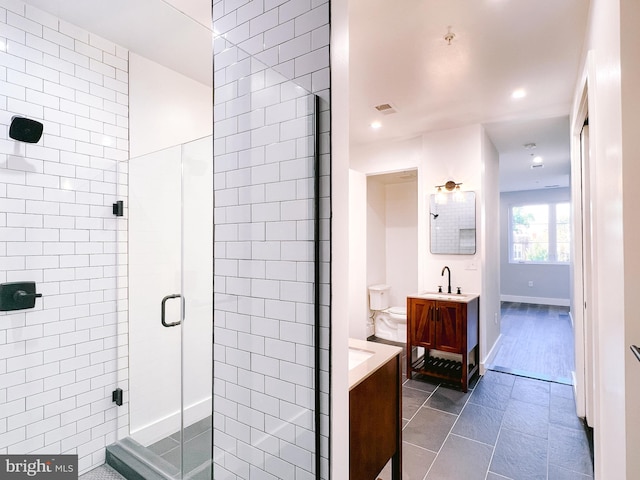 bathroom featuring tile patterned flooring, vanity, an enclosed shower, and toilet