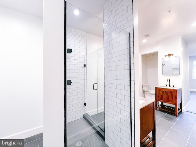 bathroom featuring tile patterned flooring, vanity, toilet, and a shower with shower door