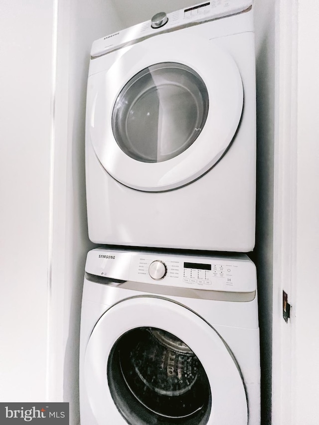 clothes washing area featuring stacked washing maching and dryer