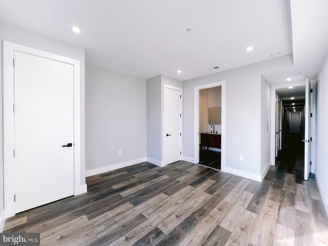 unfurnished bedroom with dark hardwood / wood-style flooring and ensuite bathroom