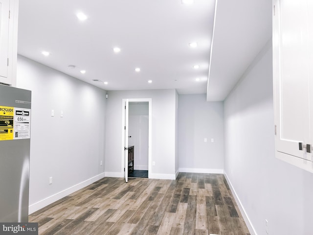 basement featuring stainless steel refrigerator and wood-type flooring