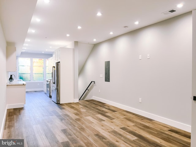 unfurnished living room featuring light wood-type flooring and electric panel