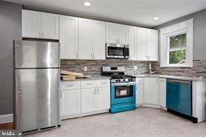 kitchen with decorative backsplash, stainless steel appliances, and white cabinets