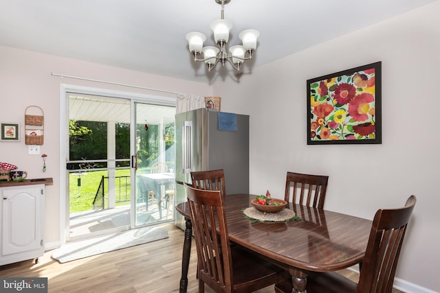 dining area with an inviting chandelier, light wood-style floors, and baseboards