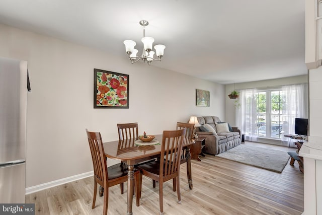 dining space featuring a notable chandelier, baseboards, and light wood-type flooring