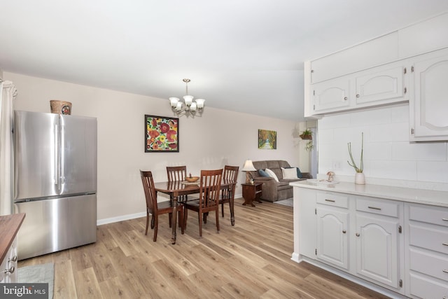 dining area featuring light wood finished floors, an inviting chandelier, and baseboards