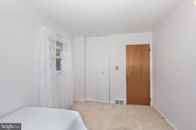 carpeted bedroom featuring visible vents and a closet