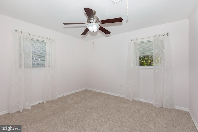 empty room featuring baseboards, a ceiling fan, a healthy amount of sunlight, and carpet floors