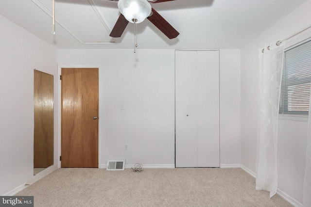 unfurnished bedroom featuring attic access, light colored carpet, visible vents, and a closet