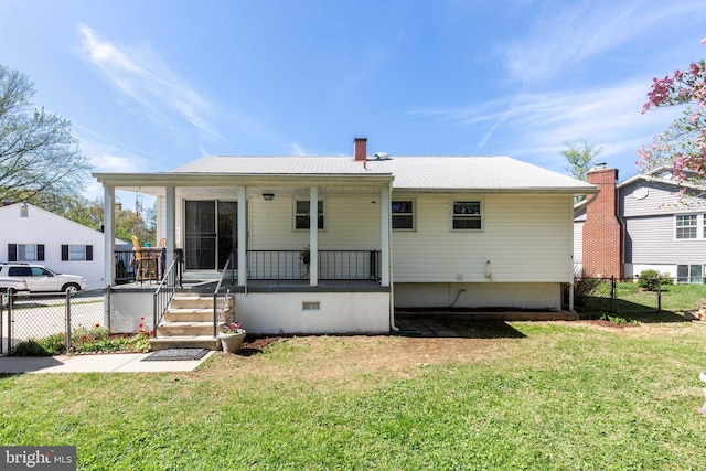 back of property with fence, covered porch, and a lawn