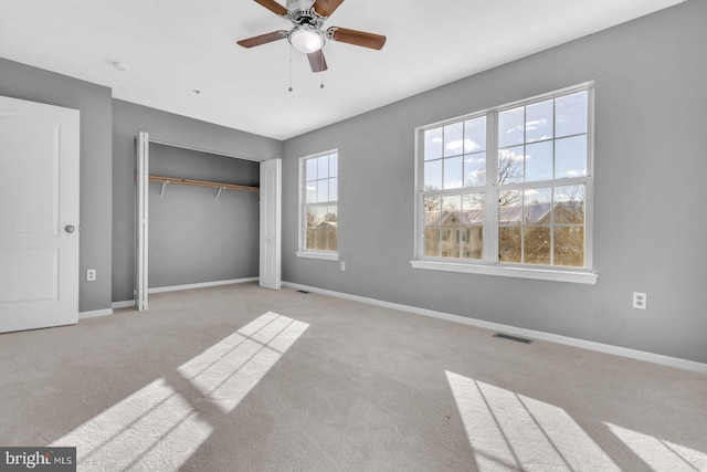 unfurnished bedroom featuring a closet, ceiling fan, and light colored carpet