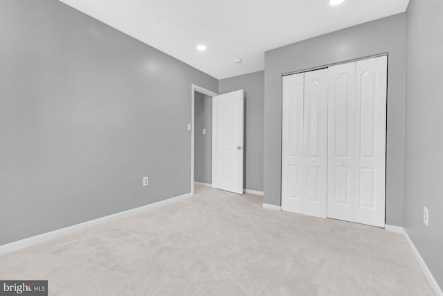 unfurnished bedroom with light carpet and a closet