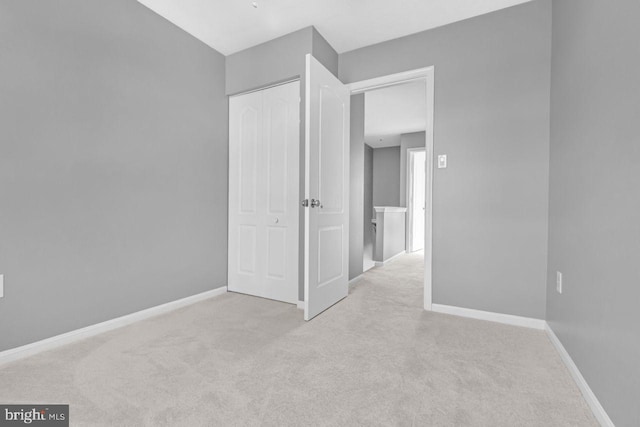 unfurnished bedroom with light carpet and a closet