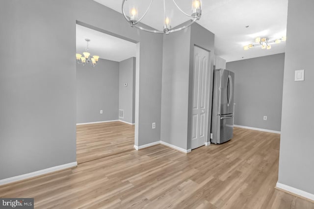 empty room featuring light hardwood / wood-style flooring and a chandelier