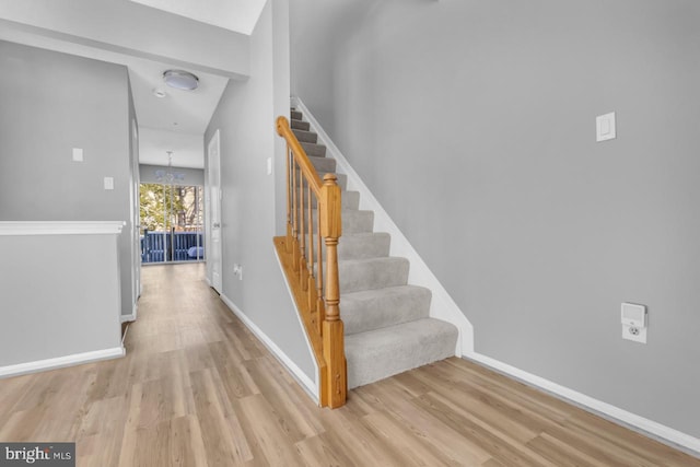 stairway featuring hardwood / wood-style floors and a chandelier