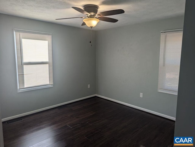 spare room with a textured ceiling, ceiling fan, and dark wood-type flooring