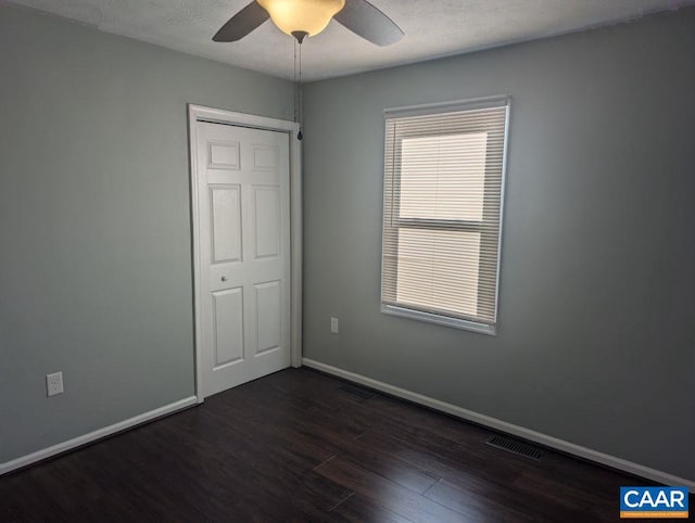 unfurnished bedroom featuring ceiling fan, a closet, and dark wood-type flooring