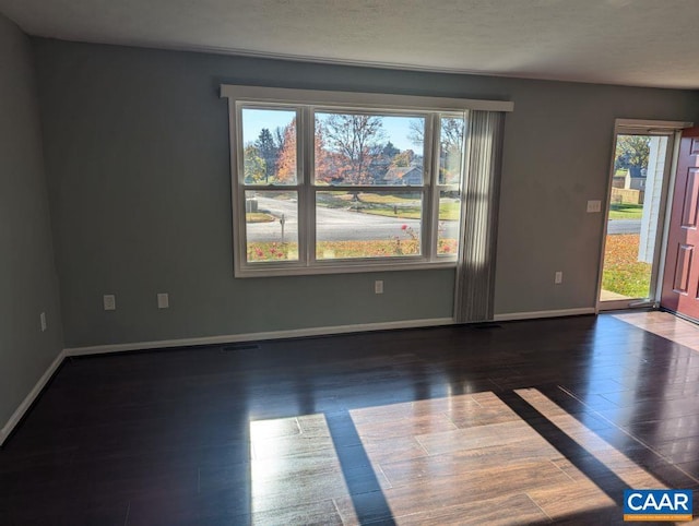 unfurnished room with dark hardwood / wood-style floors and a healthy amount of sunlight