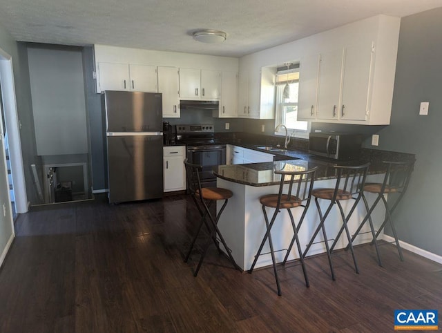 kitchen featuring white cabinetry, dark hardwood / wood-style flooring, kitchen peninsula, and stainless steel appliances