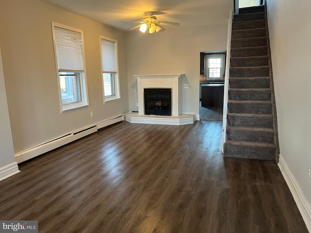 unfurnished living room with dark hardwood / wood-style floors, baseboard heating, and ceiling fan