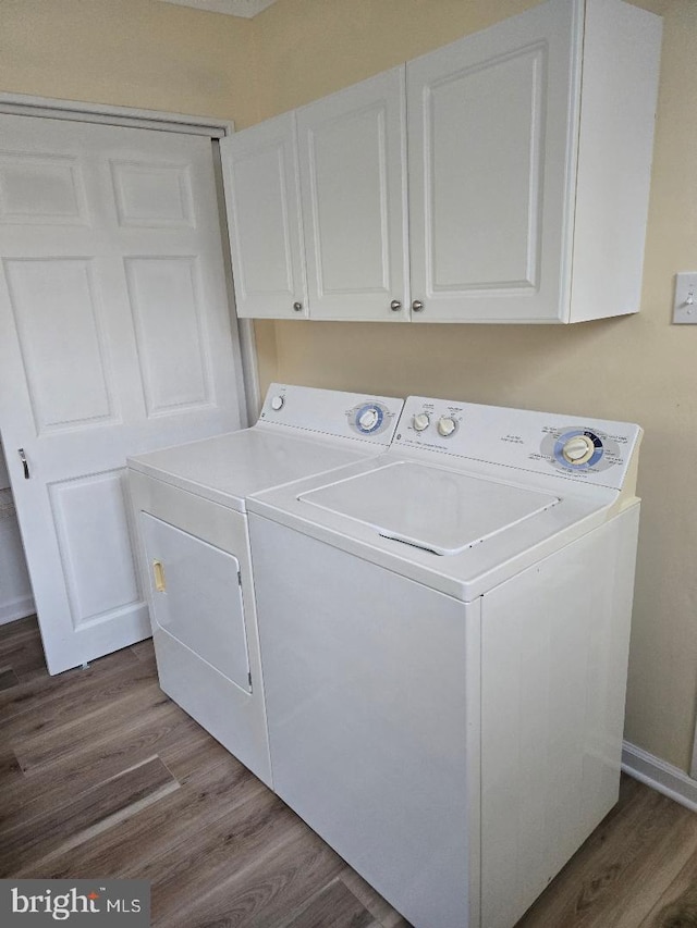 laundry area featuring cabinets, wood-type flooring, and separate washer and dryer