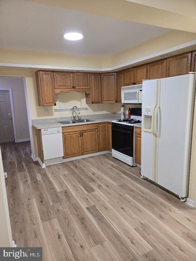 kitchen with sink, light hardwood / wood-style floors, and white appliances