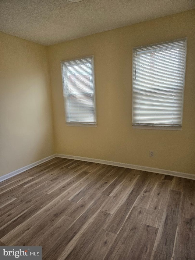 empty room with wood-type flooring and a textured ceiling