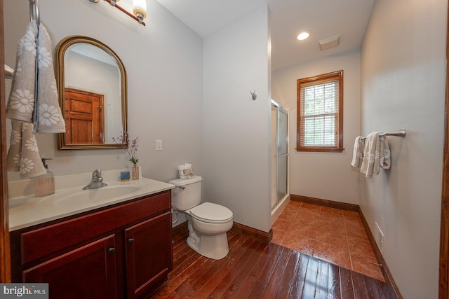 bathroom with hardwood / wood-style flooring, vanity, toilet, and walk in shower