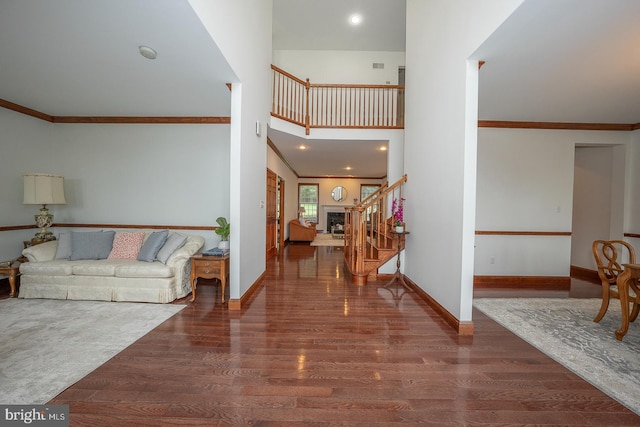 entryway with a towering ceiling, ornamental molding, and dark hardwood / wood-style floors