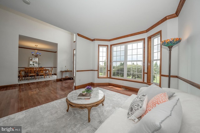 living room featuring wood-type flooring, a notable chandelier, and crown molding