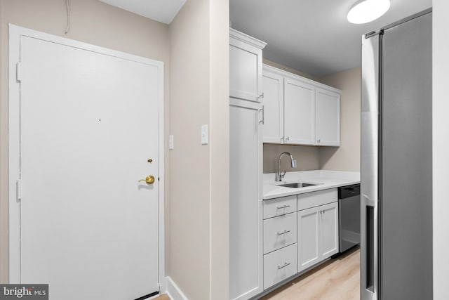 kitchen with white cabinets, stainless steel appliances, light hardwood / wood-style flooring, and sink