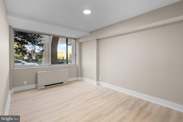 empty room featuring radiator heating unit and light hardwood / wood-style flooring