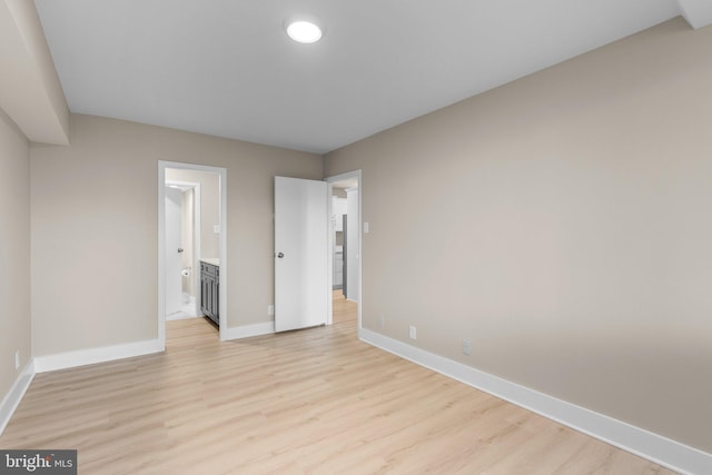 unfurnished bedroom with ensuite bath and light hardwood / wood-style floors