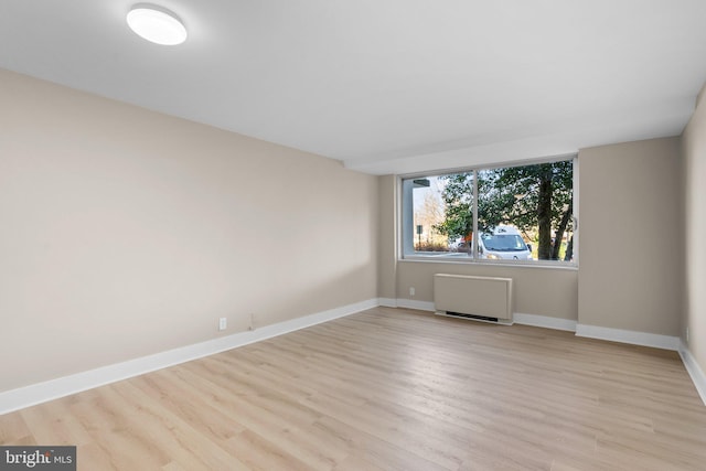 empty room featuring radiator and light wood-type flooring