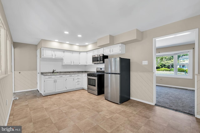 kitchen featuring light stone counters, stainless steel appliances, white cabinetry, and sink