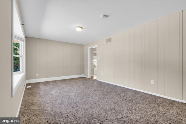 spare room with carpet flooring and wood walls