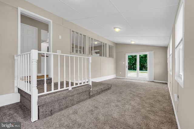 carpeted empty room featuring vaulted ceiling