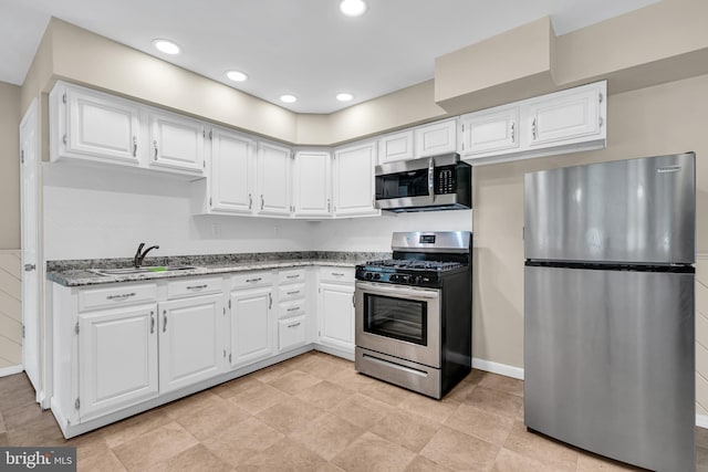 kitchen featuring white cabinetry, sink, light stone counters, and appliances with stainless steel finishes