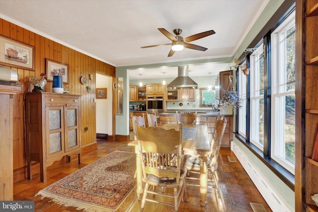 dining space featuring a wealth of natural light, ceiling fan, wood walls, and ornamental molding