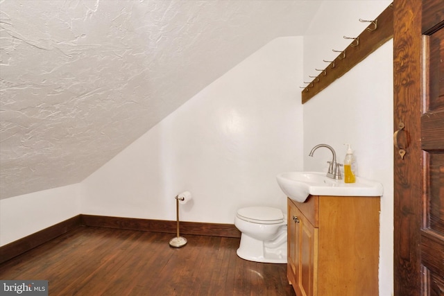 bathroom with vanity, wood-type flooring, lofted ceiling, and toilet