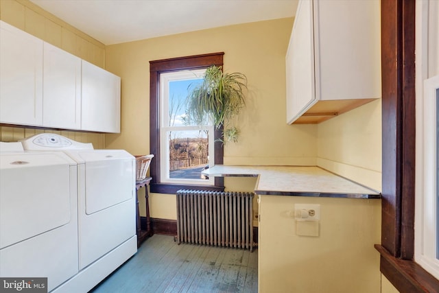 washroom featuring washer and dryer, radiator heating unit, light hardwood / wood-style floors, and cabinets