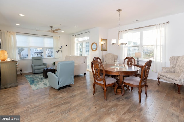 dining room featuring wood-type flooring and ceiling fan with notable chandelier