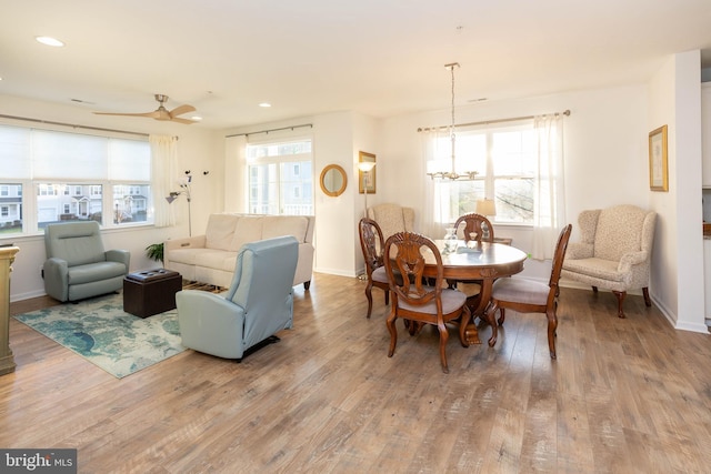 dining space with hardwood / wood-style floors, ceiling fan with notable chandelier, and a healthy amount of sunlight