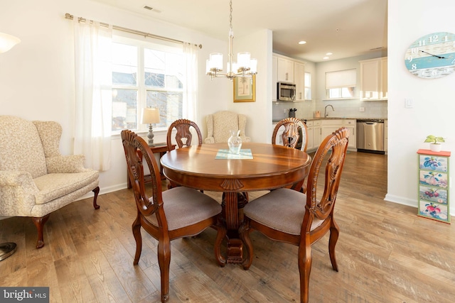 dining room featuring a notable chandelier, light hardwood / wood-style floors, and sink