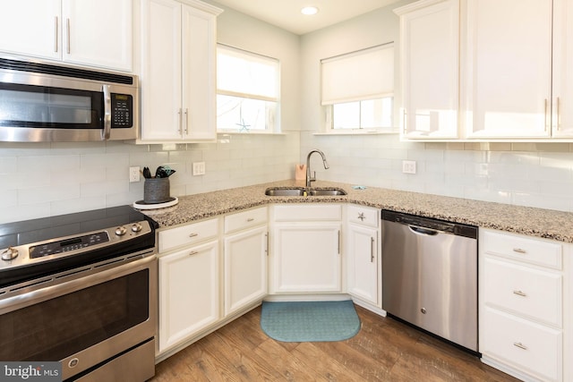 kitchen with light stone counters, sink, white cabinets, and stainless steel appliances