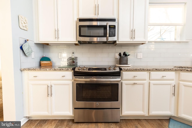 kitchen featuring light wood-type flooring, stainless steel appliances, and light stone counters