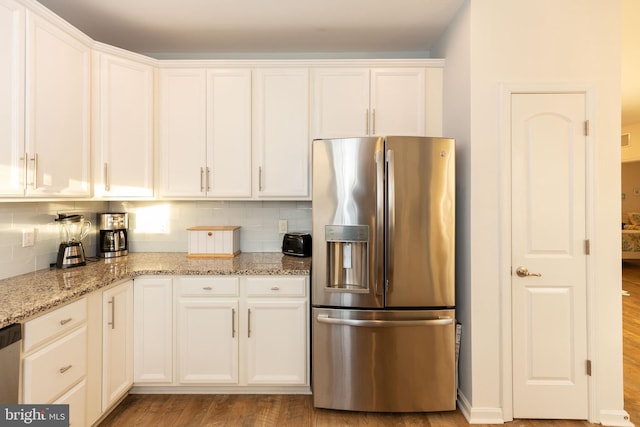 kitchen featuring appliances with stainless steel finishes, backsplash, white cabinetry, and light hardwood / wood-style flooring