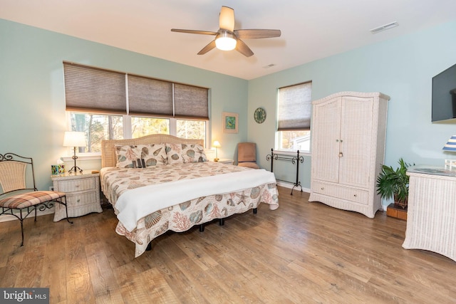 bedroom with multiple windows, hardwood / wood-style flooring, and ceiling fan